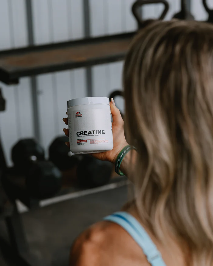 Athlete holding Leader Formulas Creatine in the gym